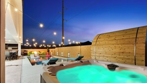 Un área de hidromasaje al aire libre con pared de madera y sillones de descanso.