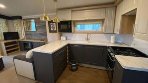 Une cuisine moderne dotée d’un îlot central, d’appareils électroménagers intégrés et de luminaires suspendus.