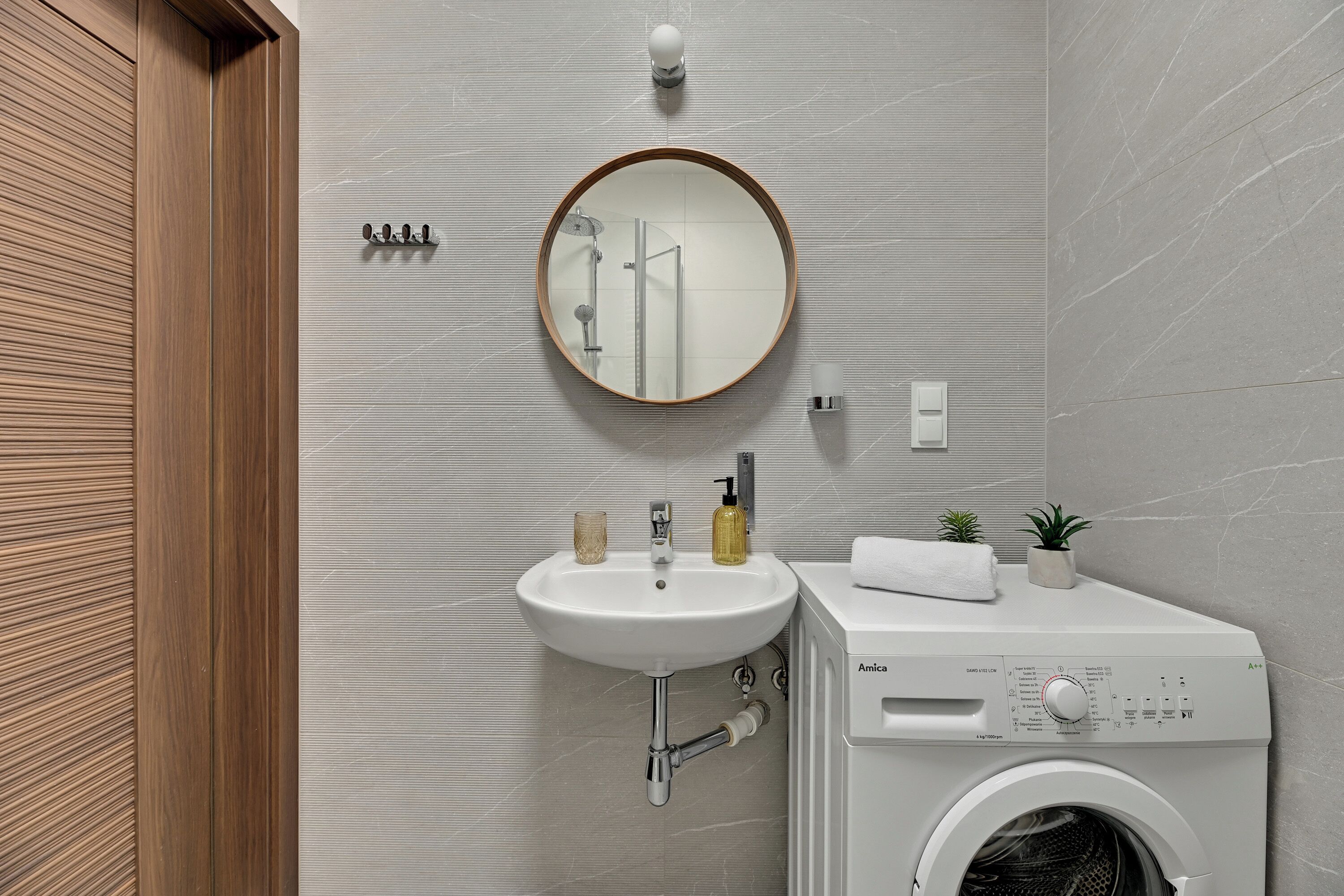 Een moderne badkamer met een wastafel, spiegel en wasmachine.