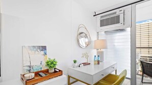 A modern room with a white desk, a yellow chair, a small plant, and a painting on the wall. - @ Marbella Lane Chic Seaside Studio w/ Pool View (Honolulu)