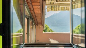 A room with a large window offering a view of a lake and mountains.