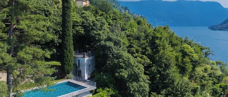 A secluded pool area surrounded by lush greenery and a mountainous backdrop.