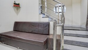 Un intérieur moderne avec un canapé, un escalier doté d’une rampe en métal et une étagère murale agrémentée d’une plante.