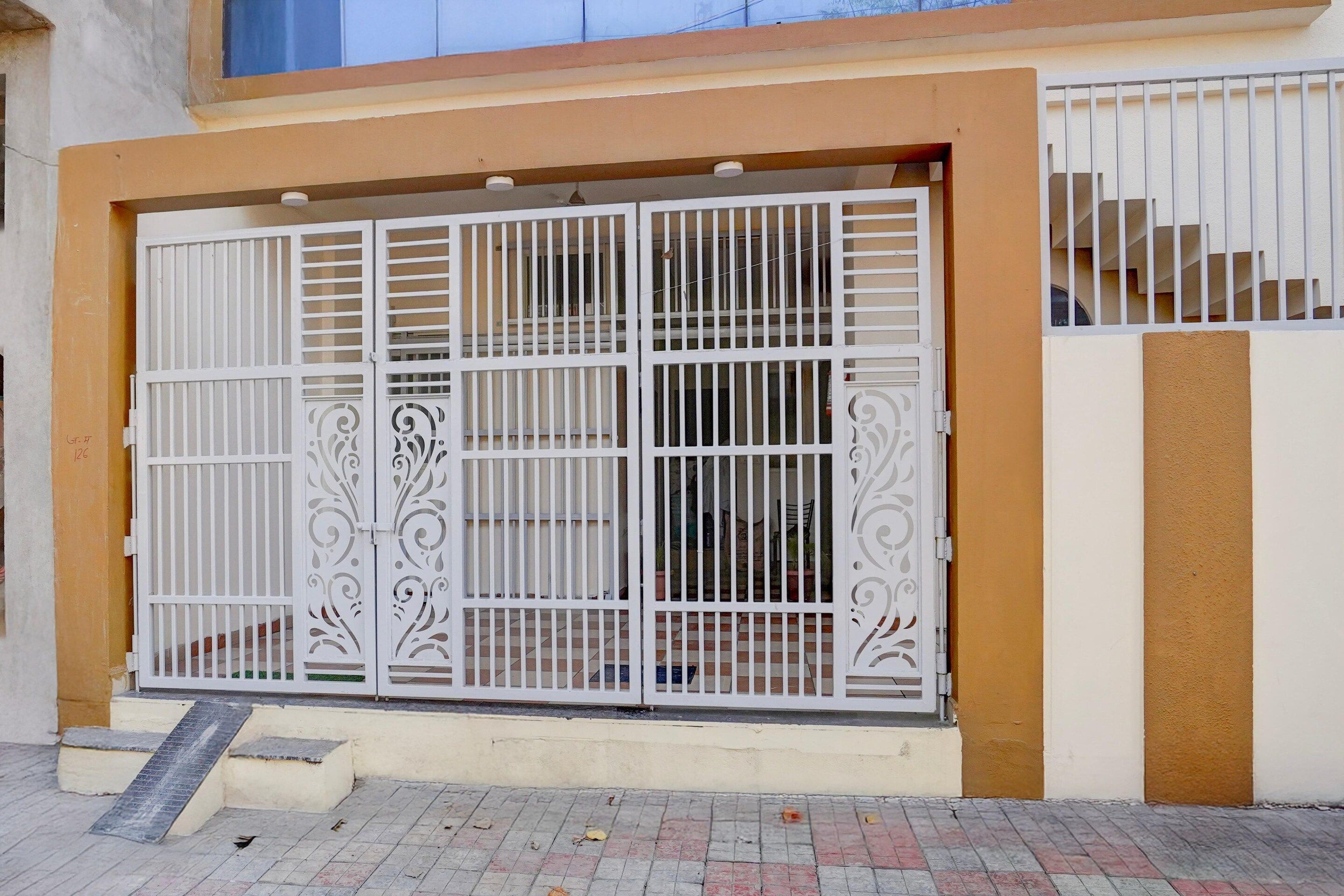 A gated entrance with a metal gate, a set of stairs, and a building facade.
