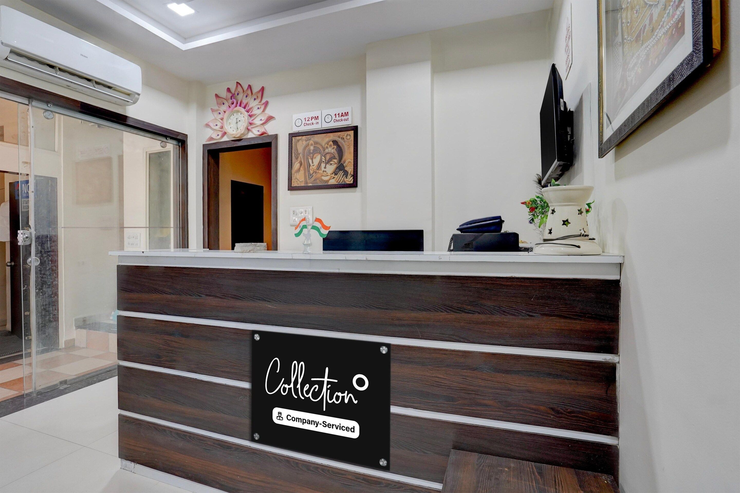 A reception desk with a sign indicating company service, a clock, and a framed artwork on the wall.