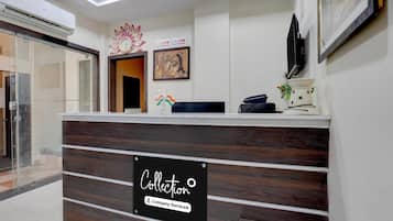 A reception desk with a sign indicating company service, a clock, and a framed artwork on the wall.