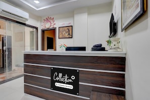 A reception desk with a sign indicating company service, a clock, and a framed artwork on the wall.