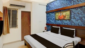 Une chambre à coucher avec un lit, une fenêtre avec des rideaux, un appareil de climatisation, un mur orné d’un motif en mosaïque et un tableau encadré.