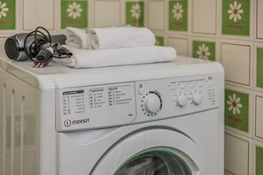 Eine Frontladewaschmaschine mit Bedienfeld, einem Netzkabel und einem gefalteten weißen Handtuch darauf.