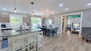A modern kitchen with a central island, dining area with chairs, and a view of the outdoors. - INDOOR POOL, HOT TUB & SAUNA!!  Welcome to Bluehaven in the Kawartha's!! (Buckhorn)