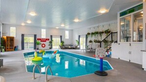 An indoor swimming pool with a blue pool, a ladder, and a slide. There are chairs and a table in the background. - INDOOR POOL, HOT TUB & SAUNA!!  Welcome to Bluehaven in the Kawartha's!! (Buckhorn)