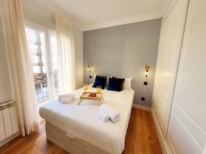 Quarto de hotel com uma cama grande, vista da cidade pela janela e parede estampada.