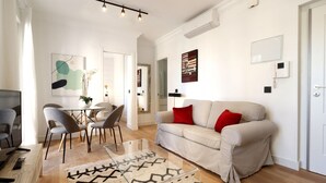 Un salon moderne comprenant un canapé, des fauteuils, une table basse en verre et un coin repas avec une table et des chaises.
