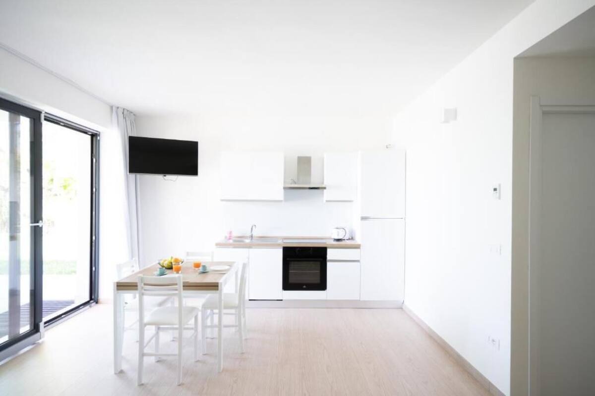 A modern kitchen with white cabinets, a black oven, and a flat-screen TV mounted above the counter.