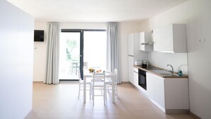A modern kitchen with white cabinets, a sink, and a dining area with a table and chairs. - Agriturismo Collina del Lago (Lazise)