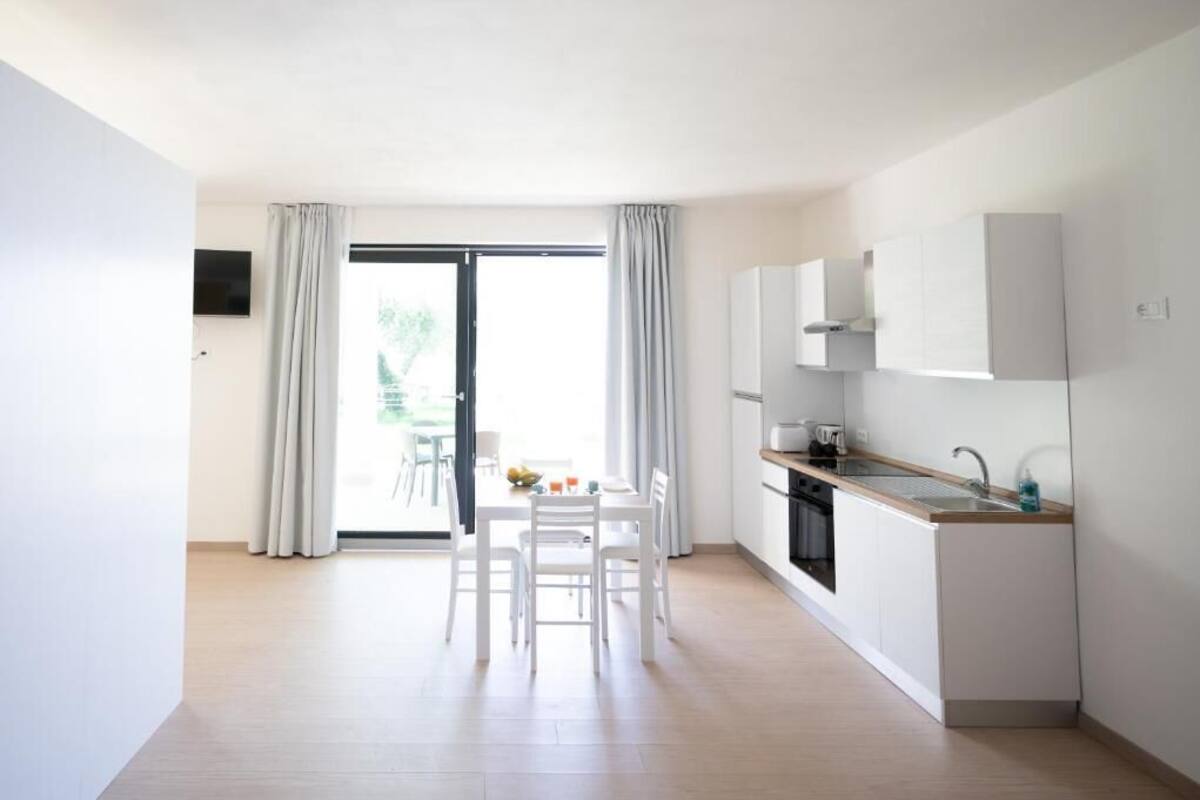 A modern kitchen with white cabinets, a sink, and a dining area with a table and chairs.