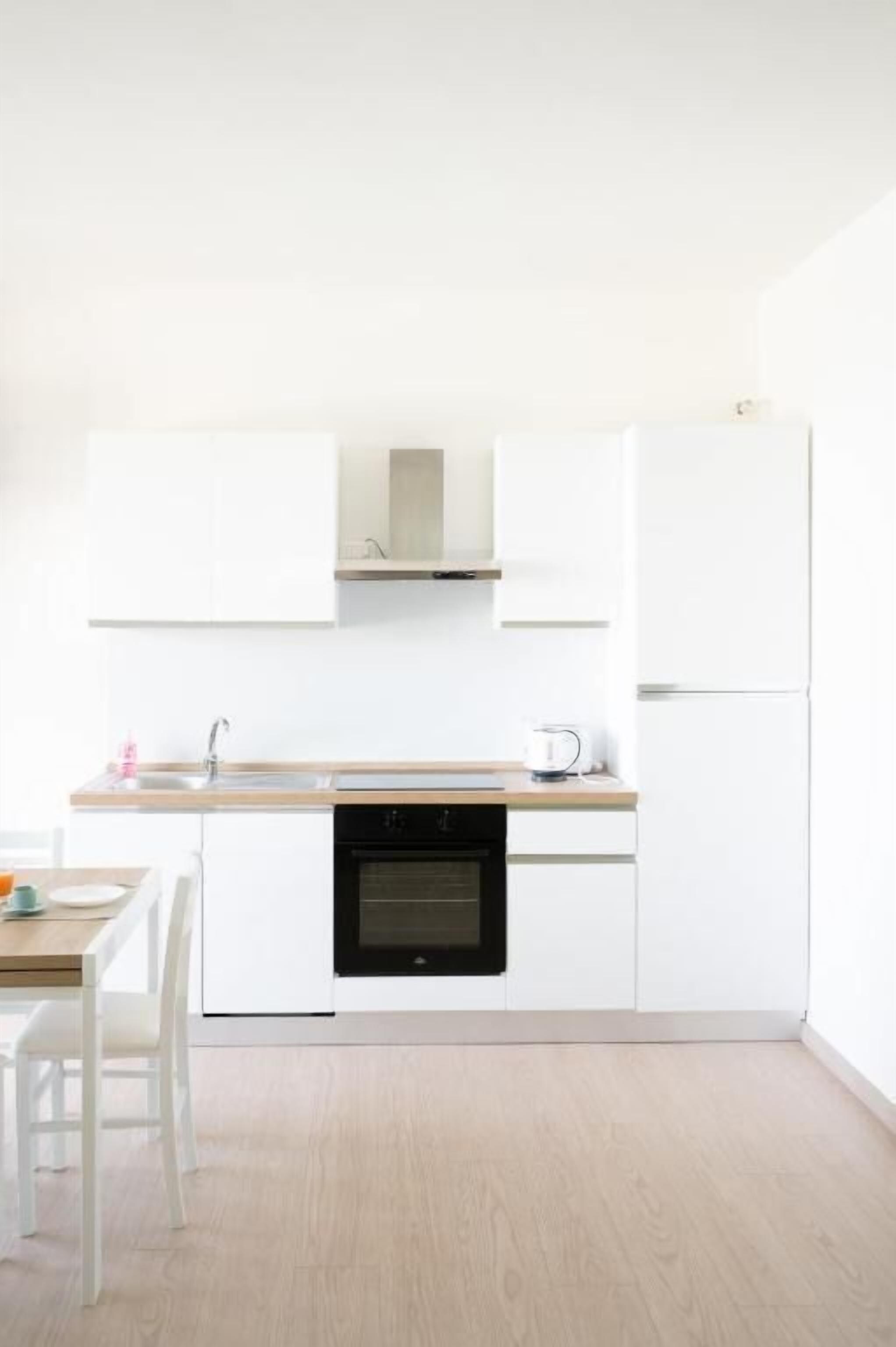 Een moderne keuken met witte kastjes, een ingebouwde oven en een houten aanrecht.