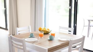 A breakfast table with white chairs, a wooden table, and a bowl of fruit. - Agriturismo Collina del Lago (Lazise)