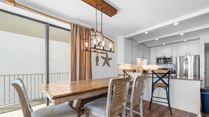Een moderne keuken met witte kastjes, een houten eettafel en een hanglamp.