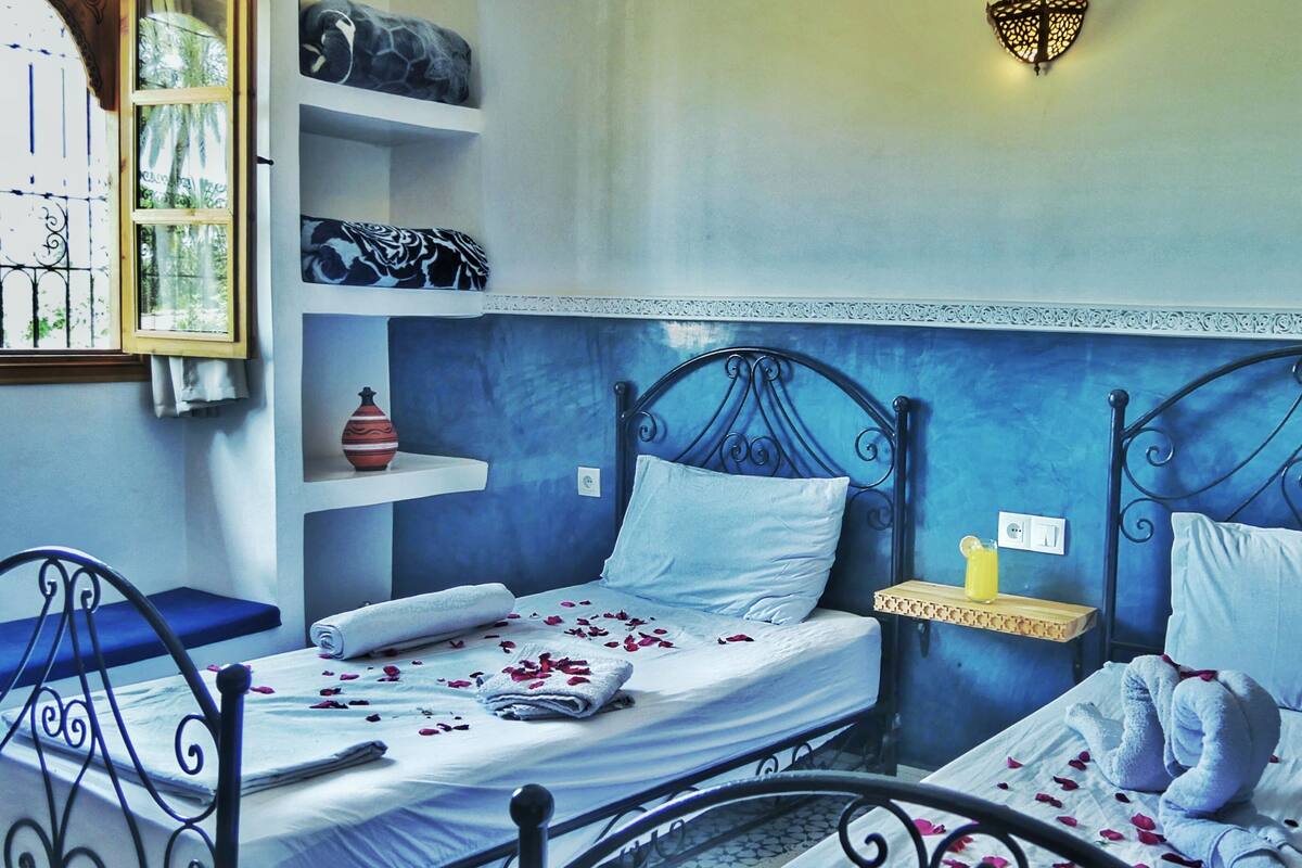 A bedroom with two beds, a bedside table, a chair, and a decorative wall.