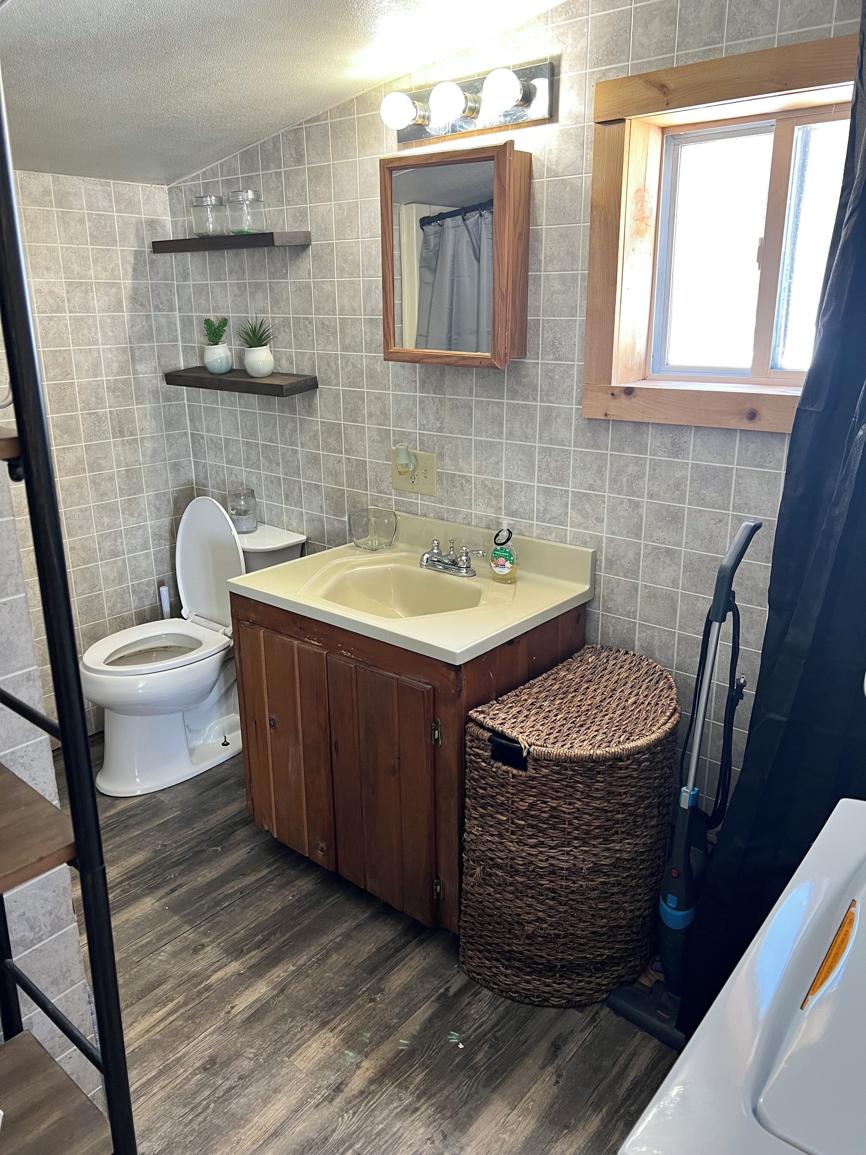 Une salle de bain avec des toilettes, un lavabo et un panier en osier.