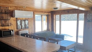 A kitchen with a granite countertop, a microwave, and a bar stool. - Cozy 2-bedroom lakeside cabin with direct trail access (Ashland)
