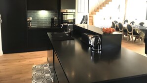 Une cuisine moderne avec un plan de travail noir, une bouilloire et un grille-pain.