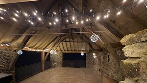 Une pièce mansardée avec un plafond en bois incliné, des murs en pierre et un plancher à motifs.