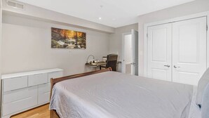 Ein Schlafzimmer mit Bett, Schreibtisch, Stuhl und Kleiderschrank.