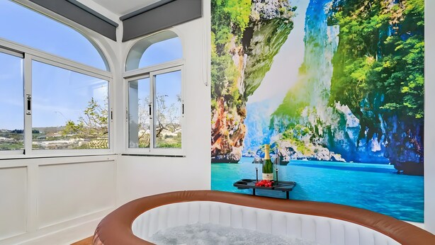 Uma área de spa com hidromassagem, um mural com paisagem e vista para o horizonte.