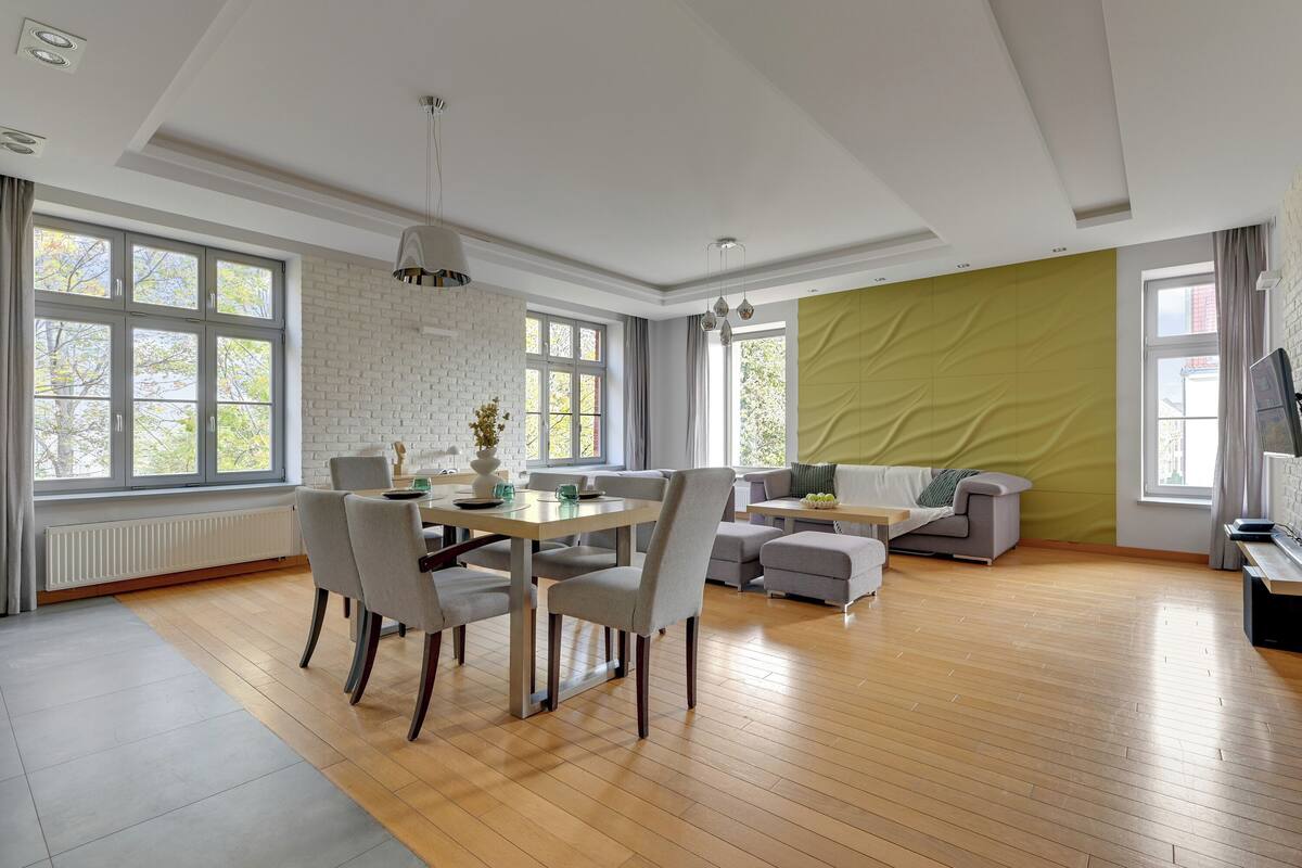 A spacious living room with a dining area, large windows, and a green accent wall.