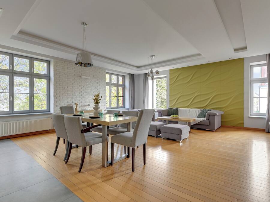 A spacious living room with a dining area, large windows, and a green accent wall.