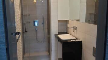 A modern bathroom with a glass-enclosed shower, a black sink, and a white toilet.