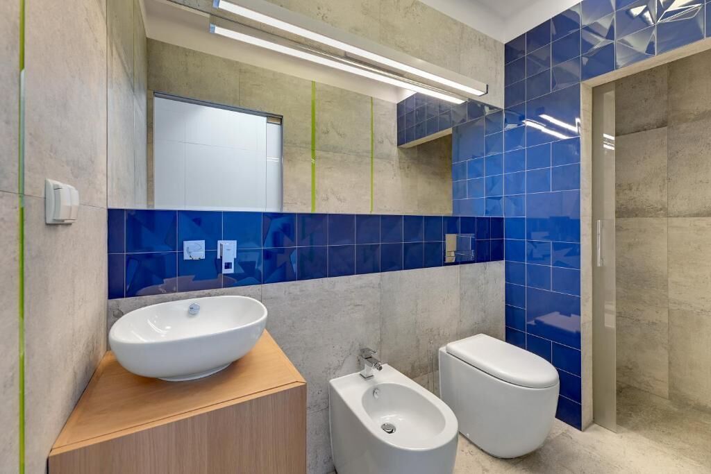 A modern bathroom with a large white sink, a bidet, and a toilet.