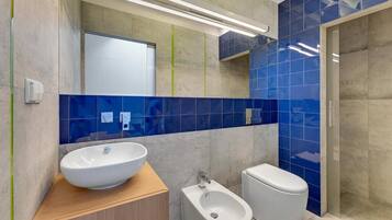 A modern bathroom with a large white sink, a bidet, and a toilet.