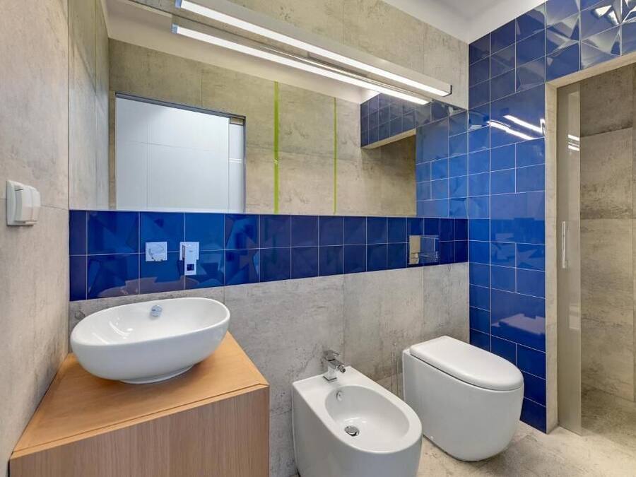 A modern bathroom with a large white sink, a bidet, and a toilet.