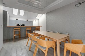 A modern kitchen with a central island, wooden chairs, and pendant lighting. - Tobiasza by Browar Hevelius Apartments (Gdańsk)