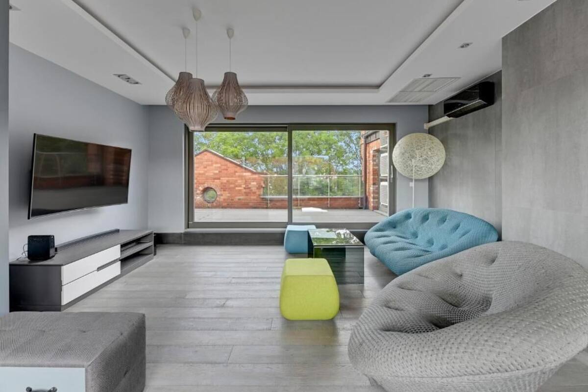 A modern living room with a flat-screen TV, a sofa, a bean bag, and a coffee table.