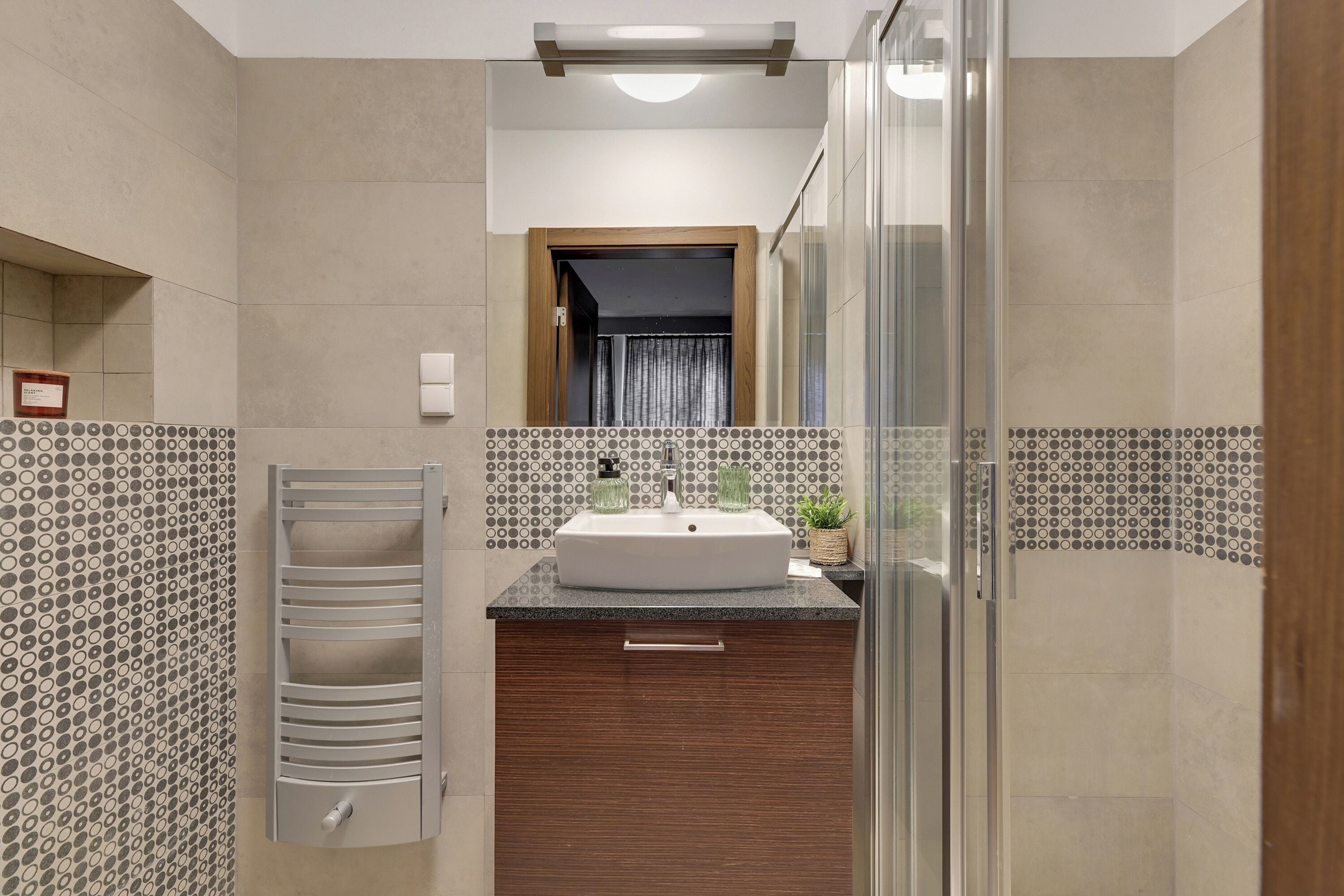 Une salle de bain moderne dotée d’un grand lavabo, d’une douche à parois de verre et d’un mur recouvert de carreaux décoratifs.