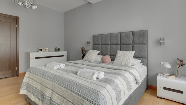 A modern bedroom with a large bed, grey headboard, bedside tables, and a hanging light fixture. - Tobiasza by Browar Hevelius Apartments (Gdańsk)