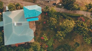 An aerial view of a house with a blue roof, surrounded by lush greenery and a small pond. - Modest family home located in a quiet neighbourhood on Calibishie Ridge. (Calibishie)