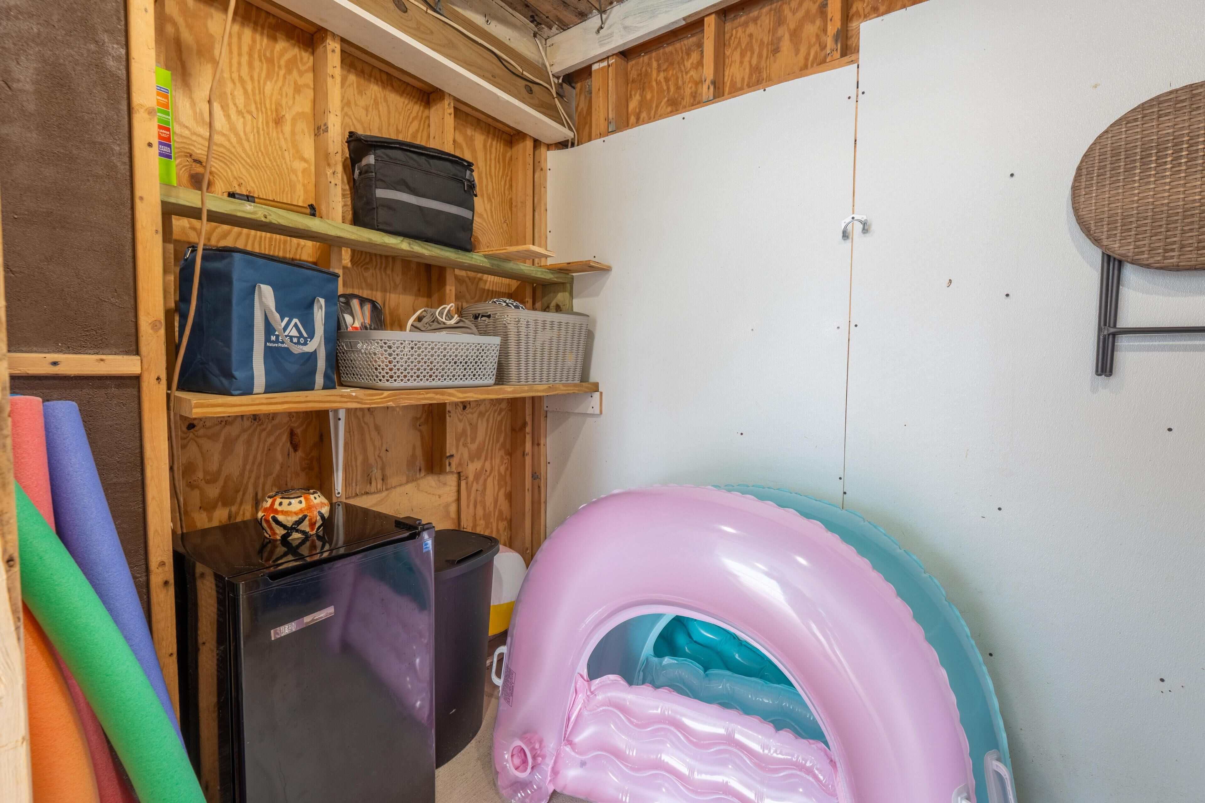 Une pièce de rangement avec des étagères, un réfrigérateur et une grande piscine gonflable.