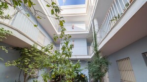 Ein mehrgeschossiges Atrium mit Kübelpflanzen, einer Treppe und Blick zum Himmel.