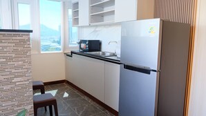 Una cocina moderna con refrigerador integrado, microondas y pileta. Hay dos taburetes y una planta en maceta.