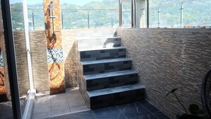 Una escalera exterior moderna con un muro de diseño y un ventanal de vidrio que da a una zona de ducha.