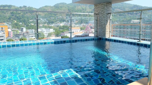 Una piscina infinita con vistas despejadas a un paisaje urbano y montañas al fondo.