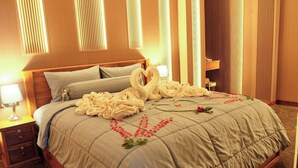 Una habitación de hotel con cama, almohadas, mesita de noche y lámpara.