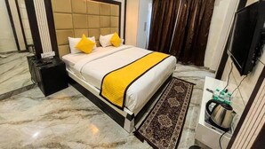 Ein Hotelzimmer mit einem großen Bett, einem Nachttisch mit Wasserkocher, einem Flachbildfernseher und einem Marmorboden.