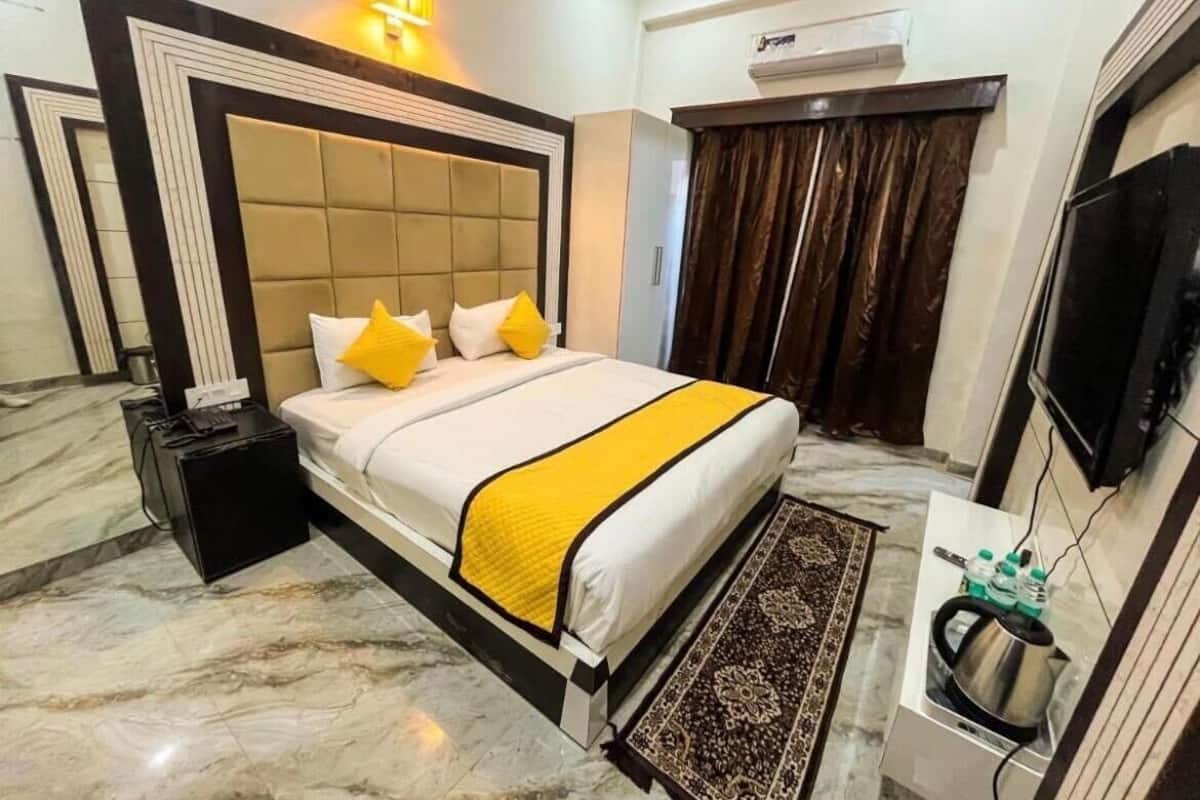 Une chambre d’hôtel avec un grand lit, une table de chevet avec une bouilloire, un téléviseur à écran plat et un sol en marbre.