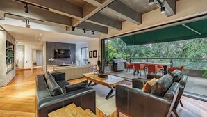 Un'ampia zona giorno dal design moderno, con un divano grande, un tavolino in legno e una sala da pranzo con sedie rosse.